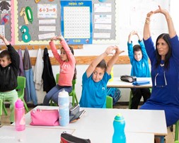 Children exercising in class with the teacher