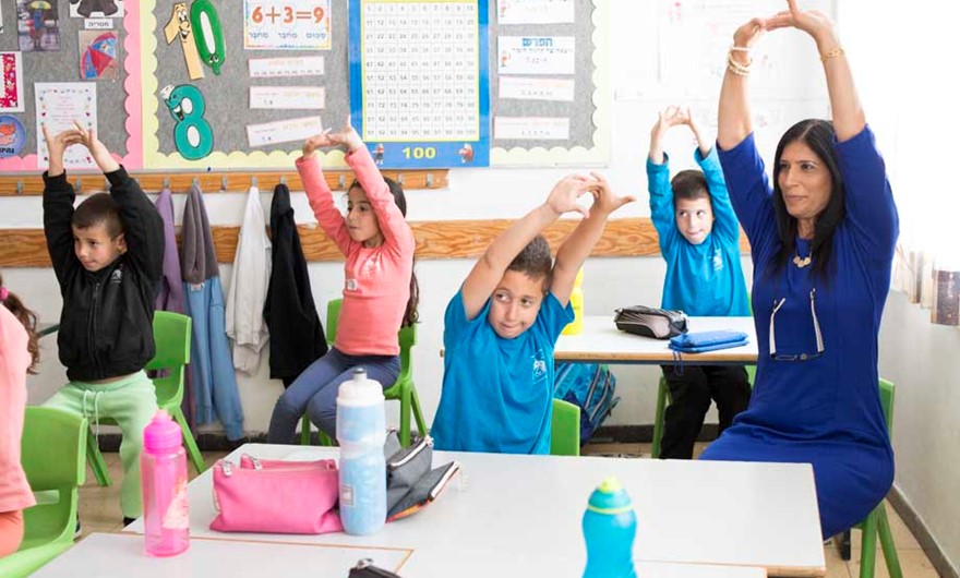 Children exercising in class with the teacher