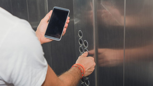 Man looking at a mobile phone in an elevator