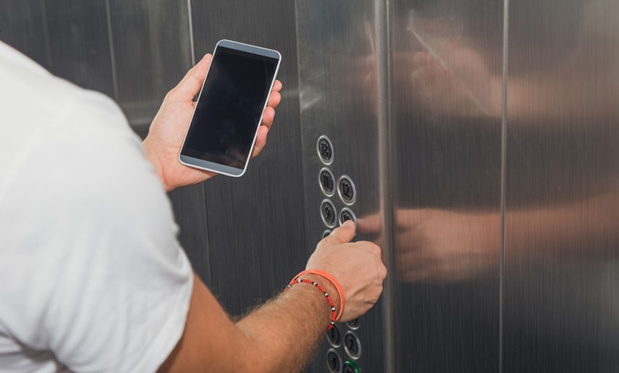 Man looking at a mobile phone in an elevator